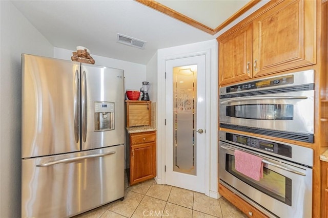 45544 Pine River Rd, Ahwahnee, CA 93601 - kitchen with appliances with stainless steel finishes, brown cabinetry, visible vents, and light tile patterned flooring