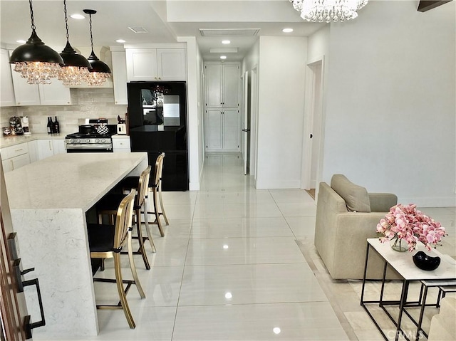 kitchen with white cabinetry, a kitchen breakfast bar, black fridge, tasteful backsplash, and gas stove