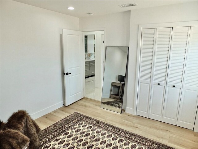 bedroom featuring light wood-type flooring, a closet, visible vents, and baseboards