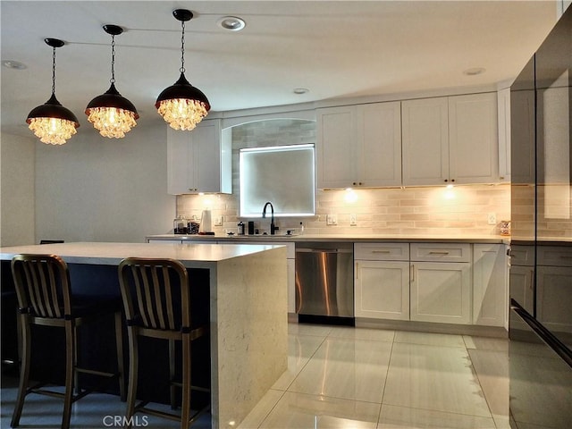 kitchen featuring pendant lighting, a breakfast bar area, backsplash, stainless steel dishwasher, and a sink