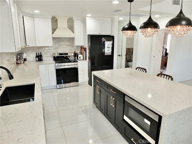 kitchen with stainless steel appliances, premium range hood, a sink, white cabinetry, and dark cabinetry