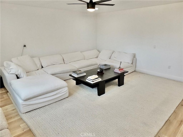living area featuring a ceiling fan, light wood-type flooring, and baseboards