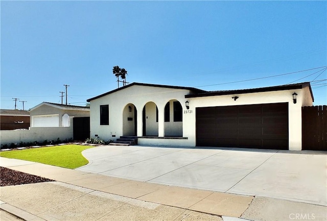 view of front of house featuring an attached garage, fence, driveway, stucco siding, and a front yard