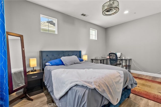 bedroom with wood finished floors, visible vents, and baseboards