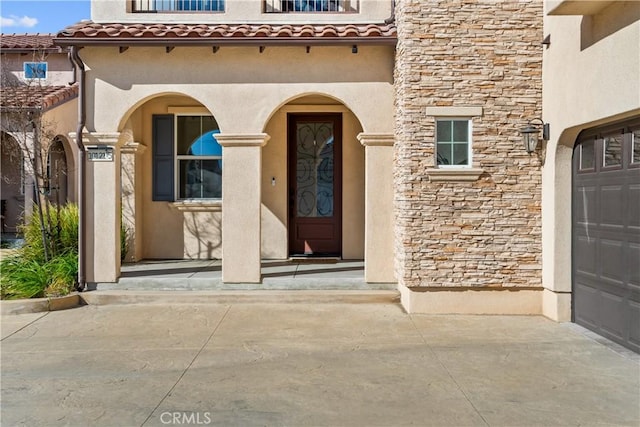 doorway to property with a tiled roof, stone siding, and stucco siding