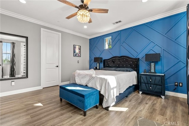 bedroom featuring wood finished floors, visible vents, multiple windows, and ornamental molding