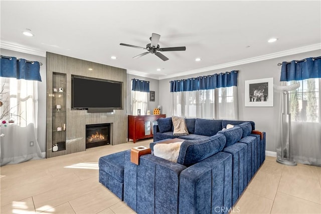 living area featuring a fireplace, ceiling fan, and ornamental molding