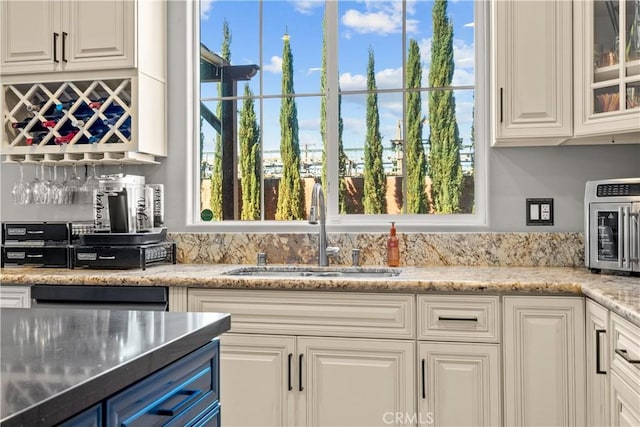 kitchen featuring light stone countertops, a toaster, a sink, white cabinets, and glass insert cabinets