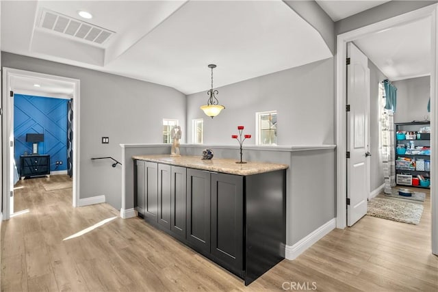 interior space featuring visible vents, baseboards, light countertops, light wood-style floors, and decorative light fixtures