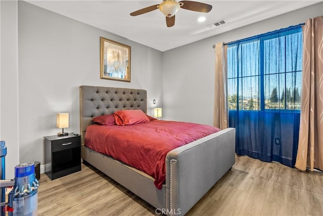 bedroom featuring light wood finished floors, visible vents, a ceiling fan, and baseboards