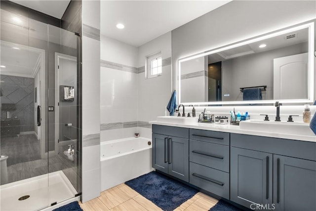 full bathroom with a sink, a jetted tub, a shower stall, and double vanity