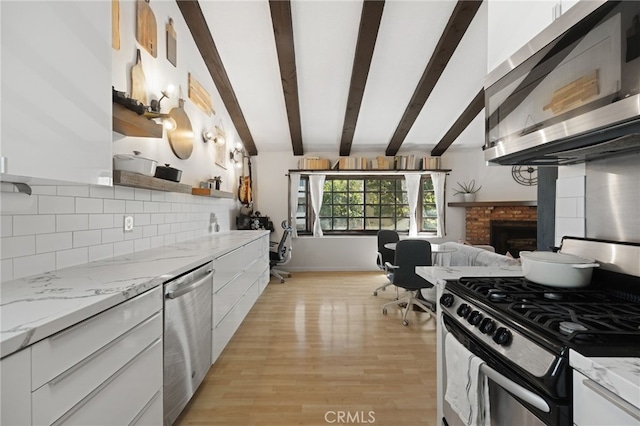 kitchen featuring a fireplace, appliances with stainless steel finishes, white cabinets, modern cabinets, and beamed ceiling