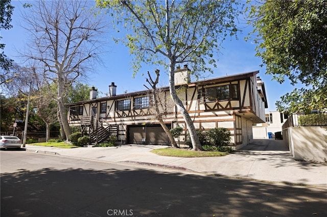 view of front of home featuring concrete driveway, a chimney, and stairs