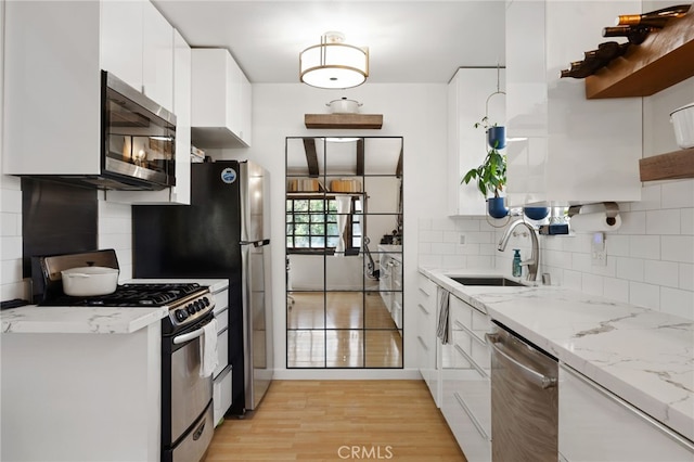 kitchen with a sink, light wood-style floors, white cabinets, appliances with stainless steel finishes, and open shelves