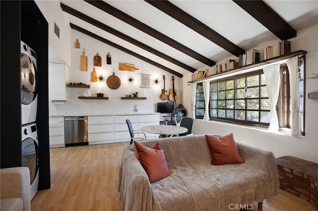 living room featuring vaulted ceiling with beams, stacked washing maching and dryer, visible vents, and light wood finished floors