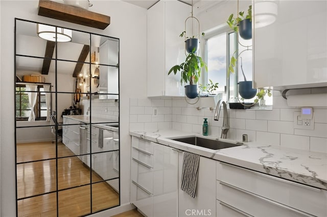 kitchen featuring a sink, modern cabinets, white cabinetry, and backsplash