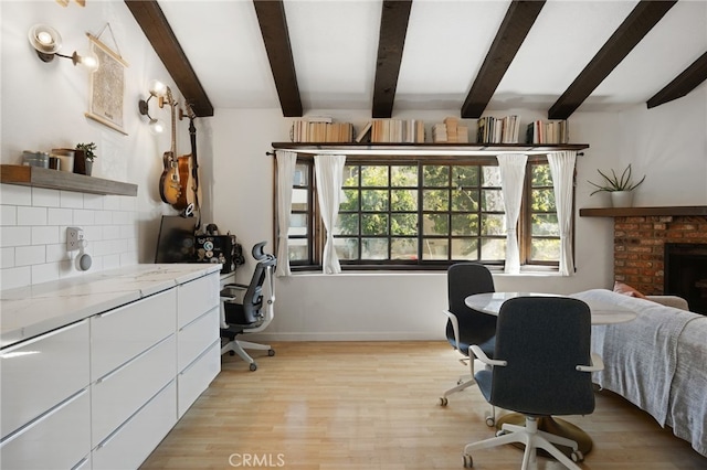 office area with beamed ceiling, a fireplace, light wood-style flooring, and baseboards