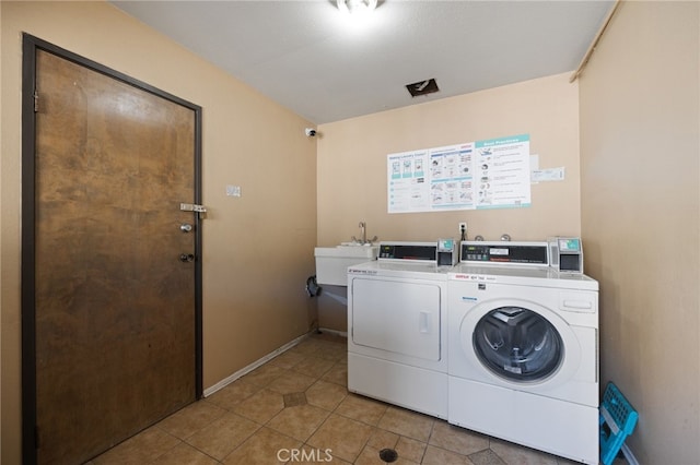 shared laundry area with tile patterned floors, baseboards, a sink, and washing machine and clothes dryer