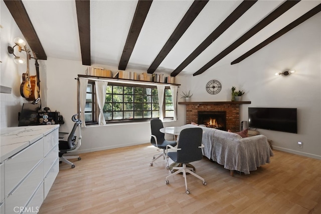 living room with lofted ceiling with beams, light wood finished floors, a brick fireplace, and baseboards