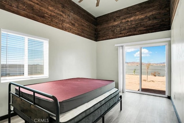 bedroom featuring a ceiling fan, access to outside, baseboards, and wood finished floors