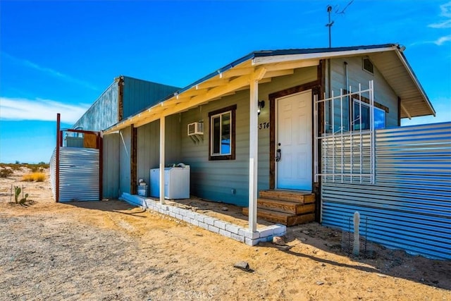 view of side of home featuring entry steps, an AC wall unit, and independent washer and dryer