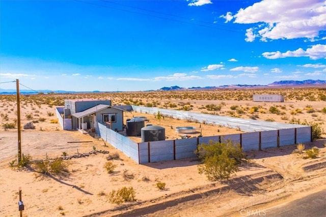 exterior space featuring a desert view, a mountain view, and fence