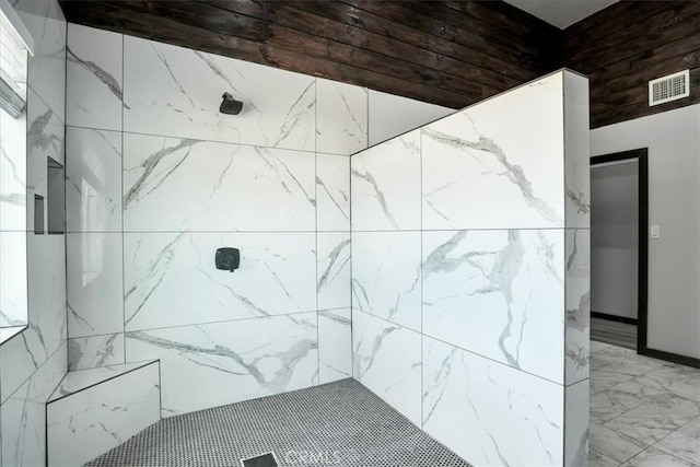 bathroom with marble finish floor, tiled shower, and visible vents