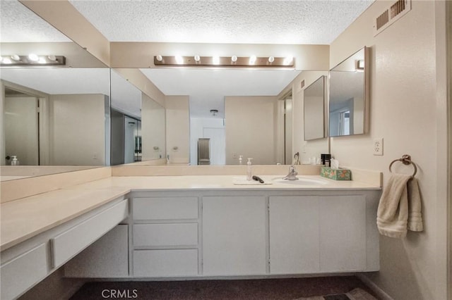 bathroom with visible vents, a textured ceiling, and vanity