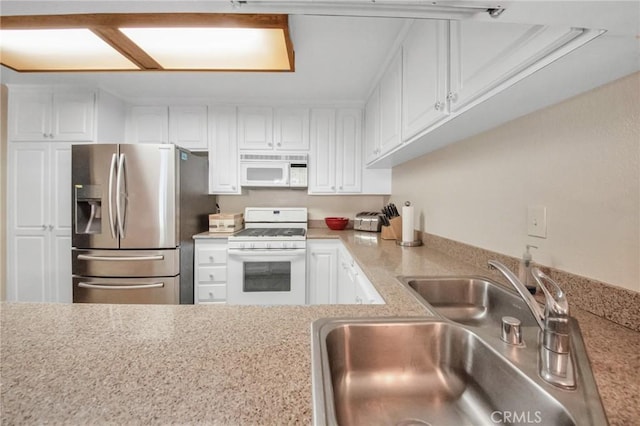 kitchen with white appliances, white cabinetry, and a sink