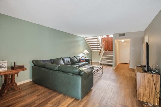 living area featuring visible vents, stairway, baseboards, and wood finished floors