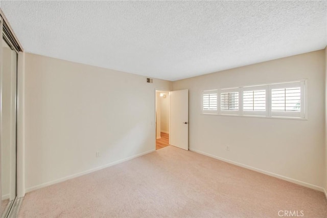 carpeted empty room with baseboards and a textured ceiling