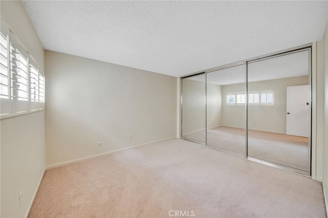 unfurnished bedroom featuring carpet, a closet, baseboards, and a textured ceiling