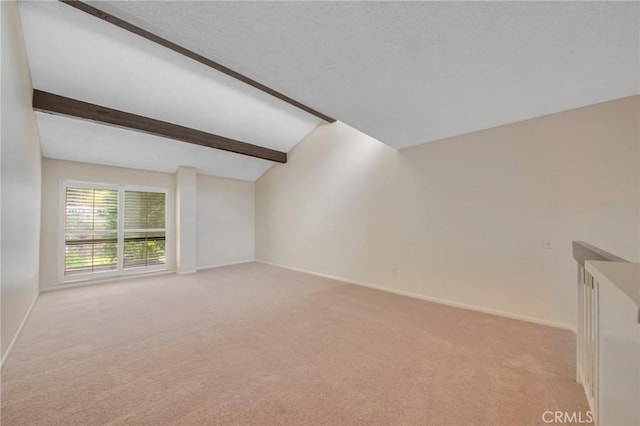 carpeted empty room featuring vaulted ceiling with beams and baseboards