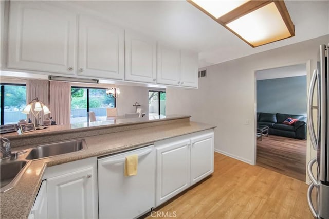 kitchen featuring visible vents, white cabinets, freestanding refrigerator, white dishwasher, and light wood-type flooring