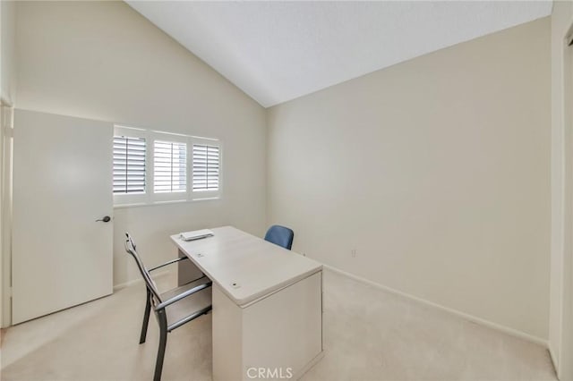 home office featuring baseboards, vaulted ceiling, and light colored carpet