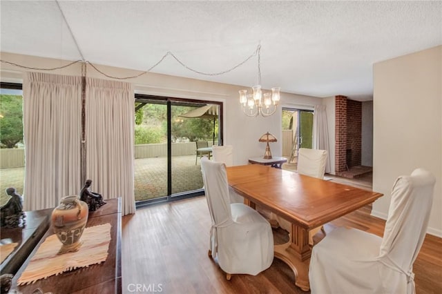 dining area with a chandelier, a textured ceiling, wood finished floors, and baseboards