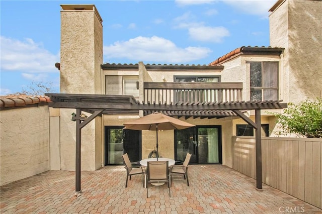 rear view of property with a patio, a tile roof, a chimney, a pergola, and stucco siding