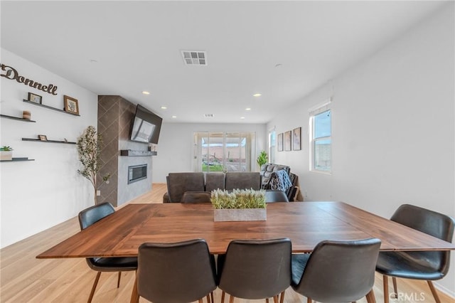 dining room featuring a large fireplace, wood finished floors, visible vents, and recessed lighting