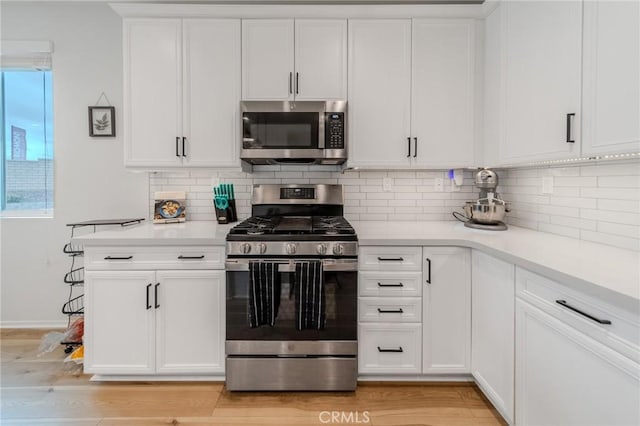 kitchen featuring light wood finished floors, white cabinetry, stainless steel appliances, and light countertops