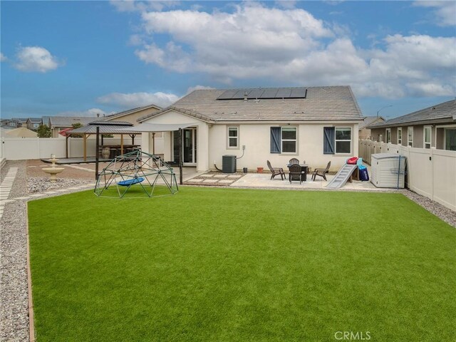 back of property with solar panels, a fenced backyard, a gazebo, a yard, and a patio area