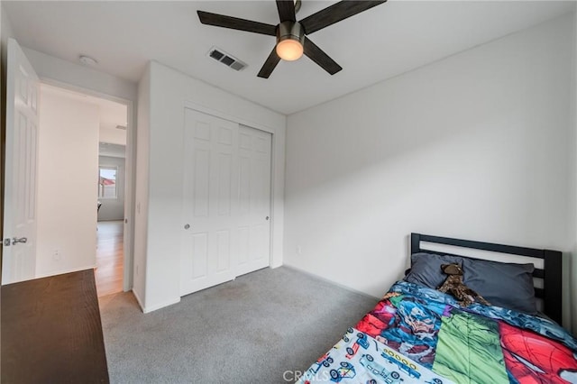 carpeted bedroom featuring a closet, visible vents, and a ceiling fan