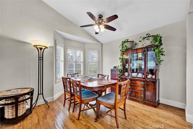 dining area with baseboards, light wood-style floors, ceiling fan, and vaulted ceiling