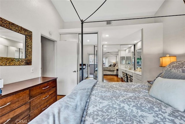 bedroom featuring visible vents, lofted ceiling, and wood finished floors