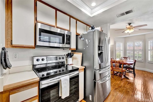 kitchen with visible vents, light wood-type flooring, a tray ceiling, light countertops, and stainless steel appliances