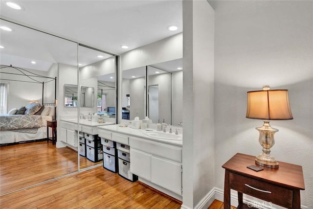 ensuite bathroom featuring vanity, wood finished floors, baseboards, recessed lighting, and connected bathroom