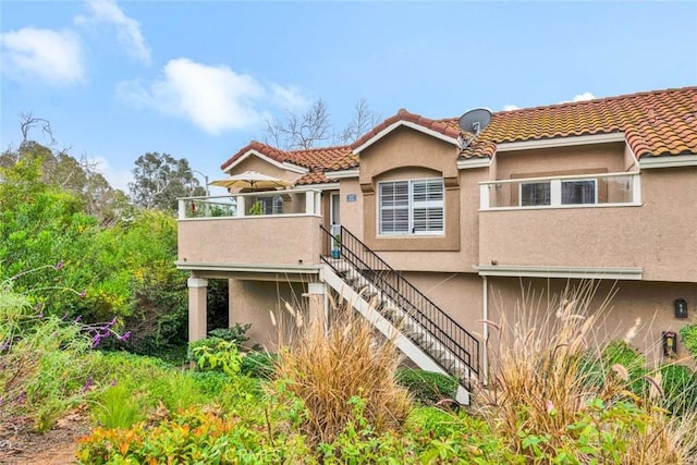 view of front of house featuring stairway, a tile roof, and stucco siding