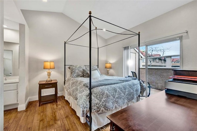 bedroom with vaulted ceiling, hardwood / wood-style flooring, and baseboards