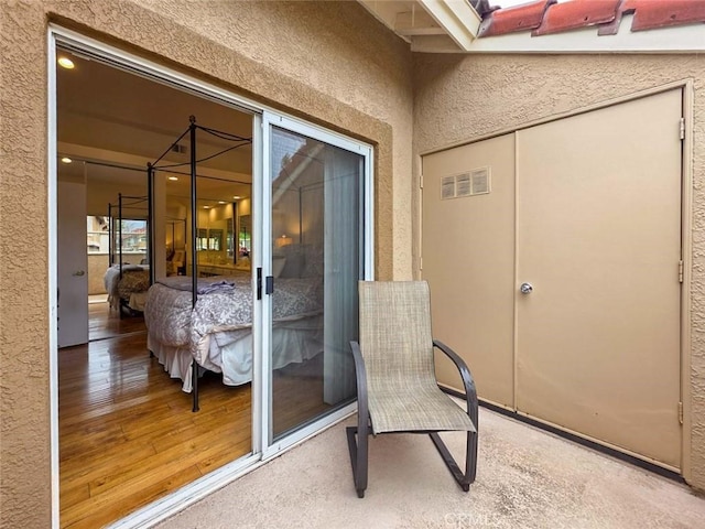 view of exterior entry with stucco siding and visible vents