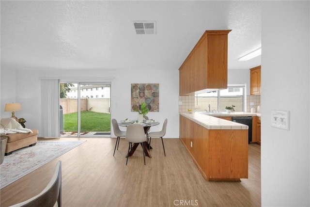 dining room with light wood finished floors, visible vents, and a textured ceiling