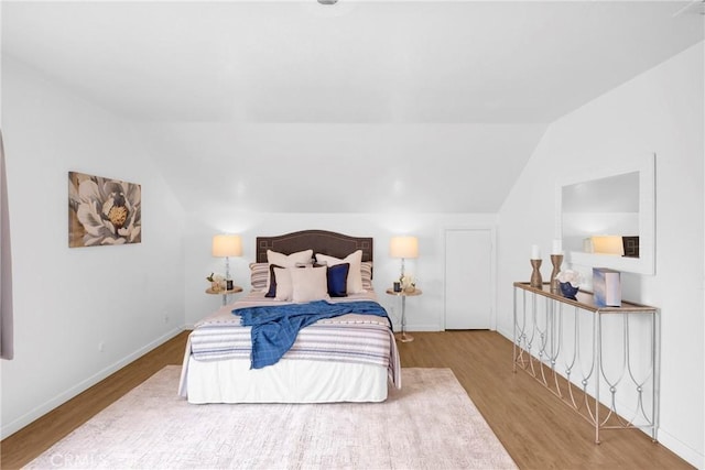 bedroom with baseboards, wood finished floors, and vaulted ceiling